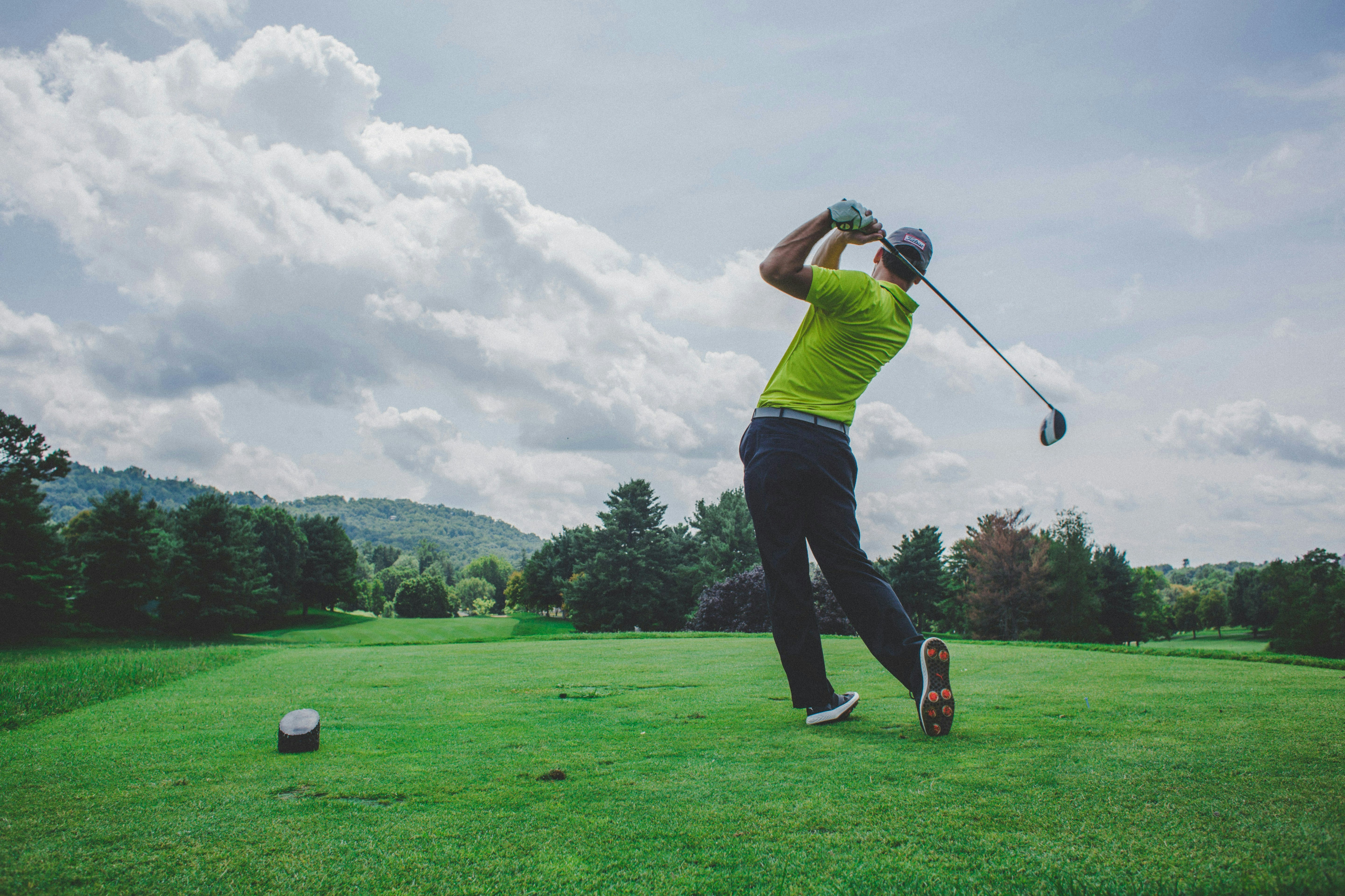Golfspieler von hinten nach Aufschlag auf grünem Rasen