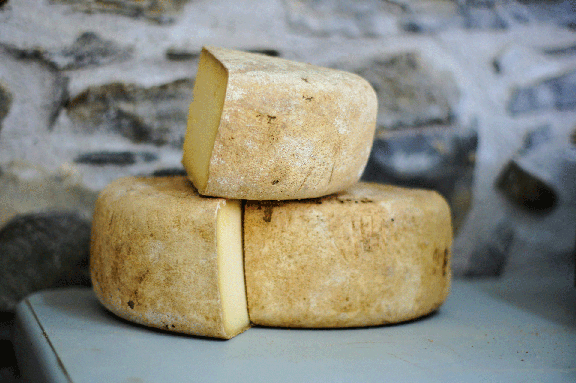 Trois meules de fromage entamées sur un fond pierreux