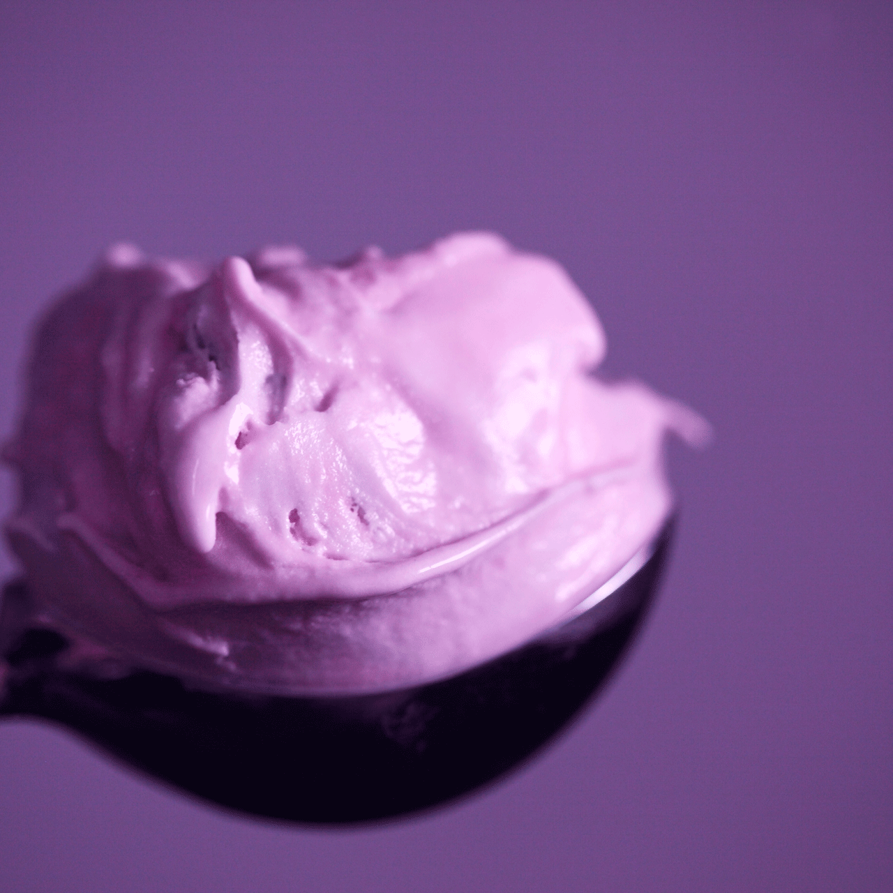 Ermitage kitchen philosophy Pink sorbet on a spoon against a purple background