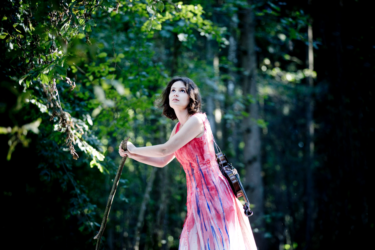 Geigerin mit rot-blauem Kleid im Wald