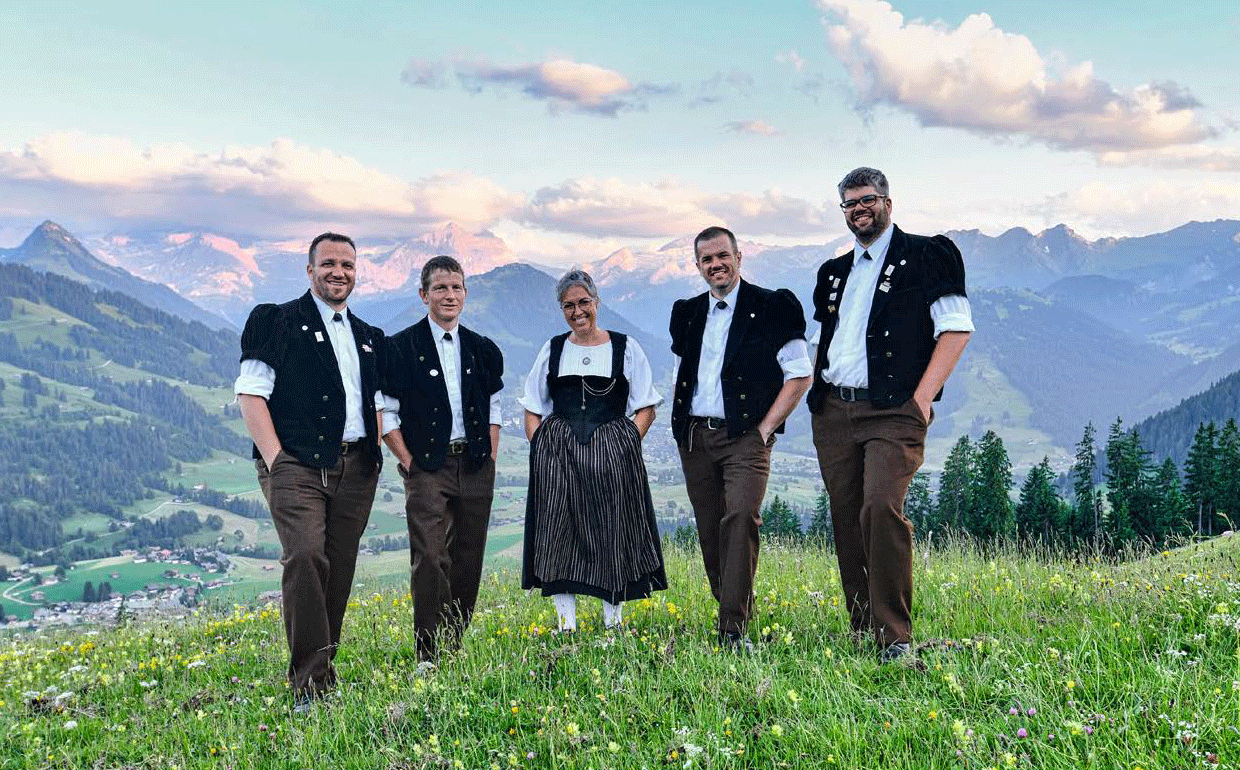 Folkloristisch angezogene Gruppe bestehend aus vier Männern und einer Frau in Berglandschaft