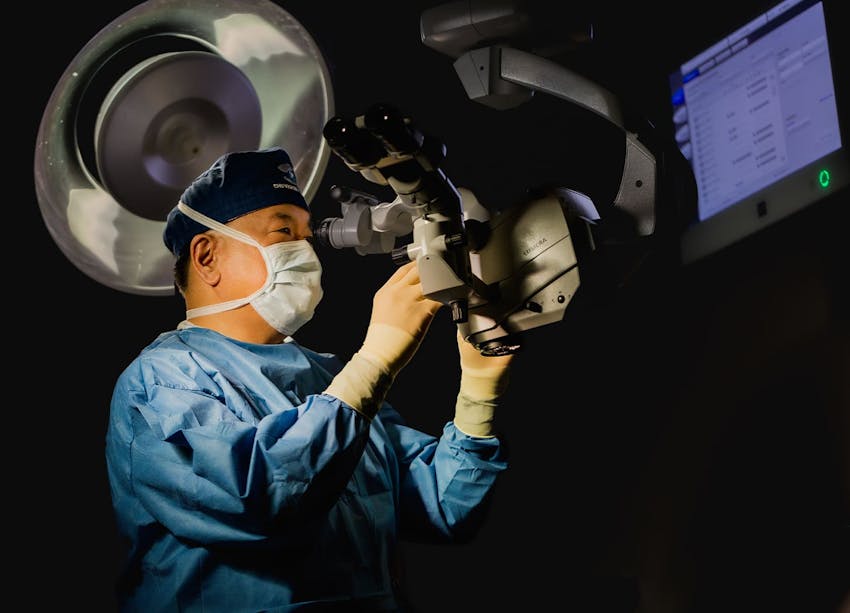 Dr. Chu looking thorugh microscope lens machine