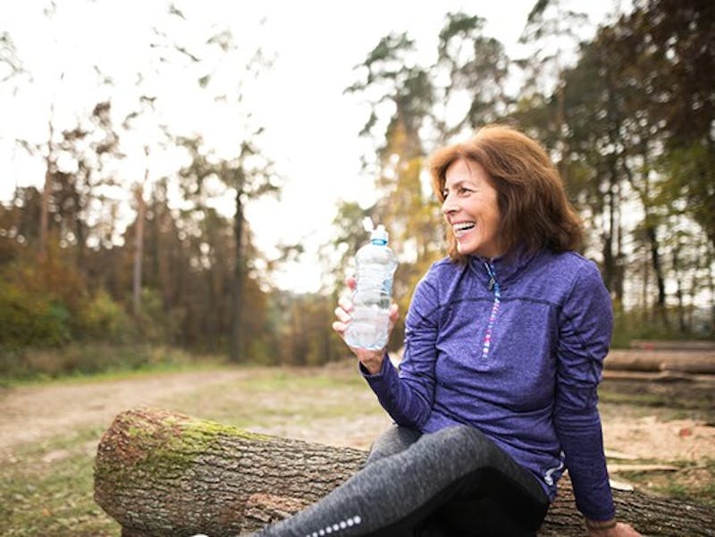 woman sitting on a log drinking water