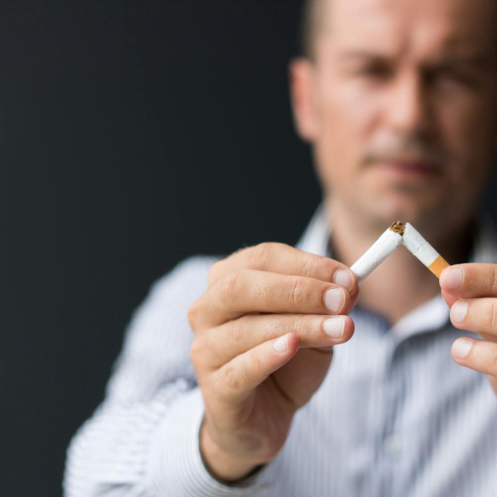 man breaking a cigarette in half
