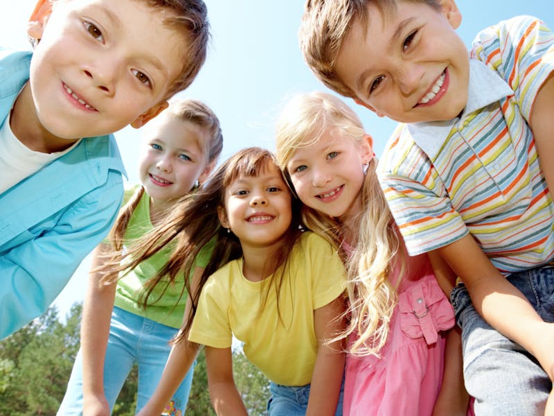 group of children that are standing together in the grass