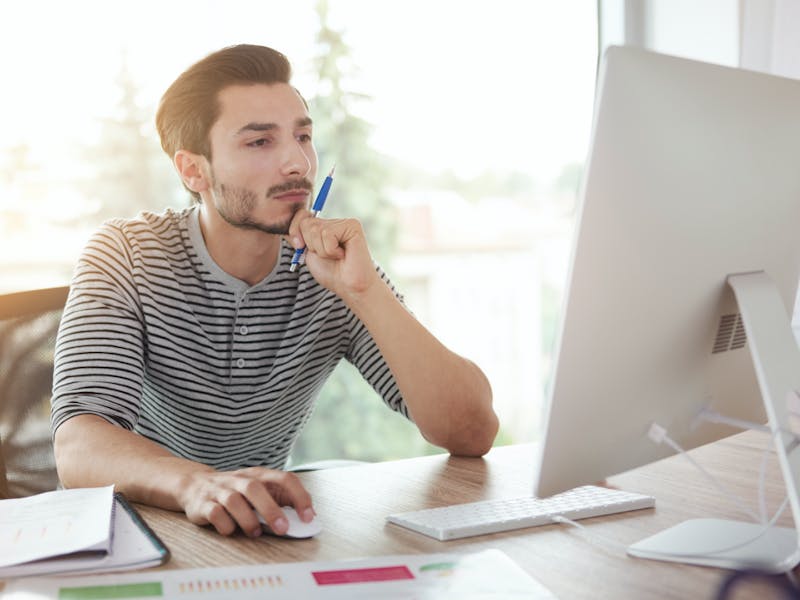 there is a man sitting at a desk with a computer and a pen