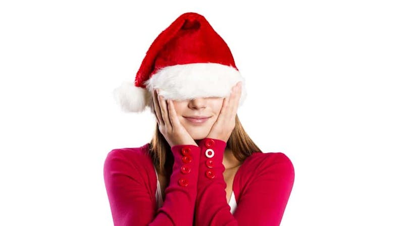 woman in a santa hat covering her eyes with her hands