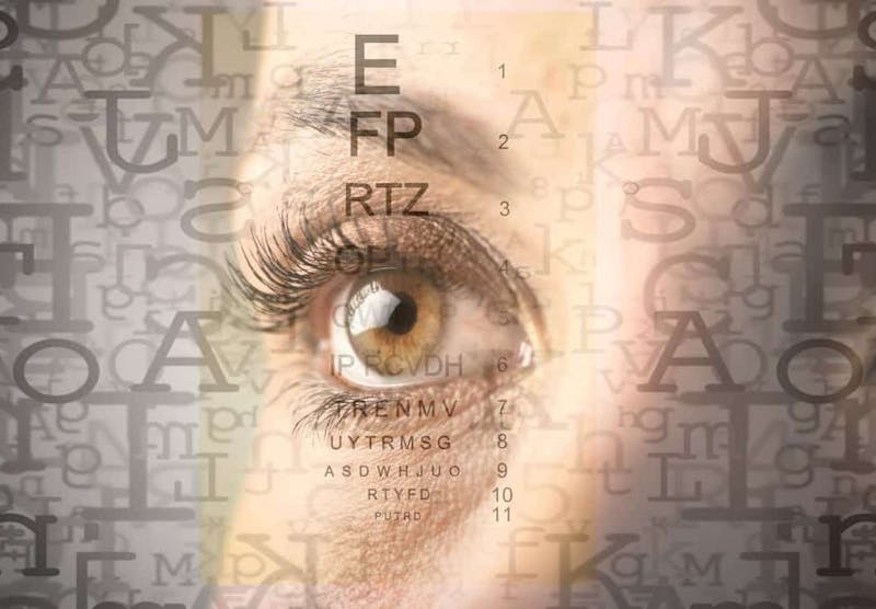 there is a woman's eye with a large eye chart faded in the background
