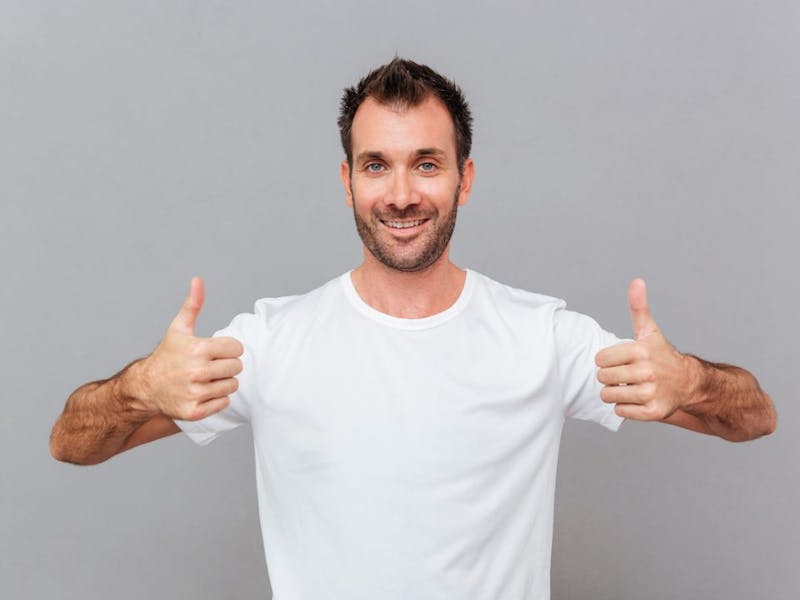 man in white shirt showing thumbs up with both hands