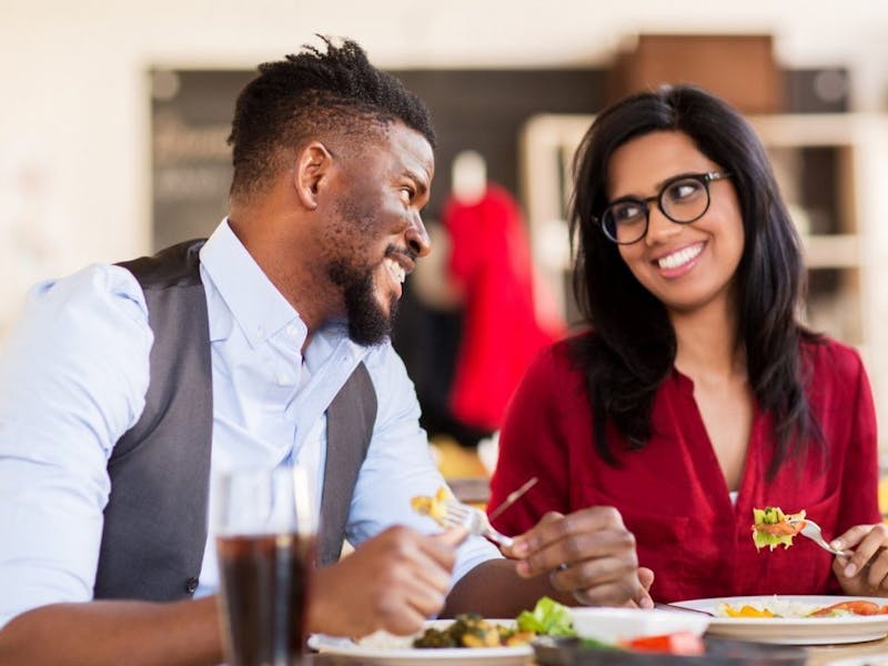 smiling couple eating at a restaurant table with plates of food