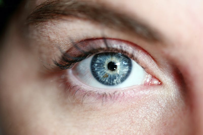 a close up of a person's eye with a reflection of another person taking a photo in it