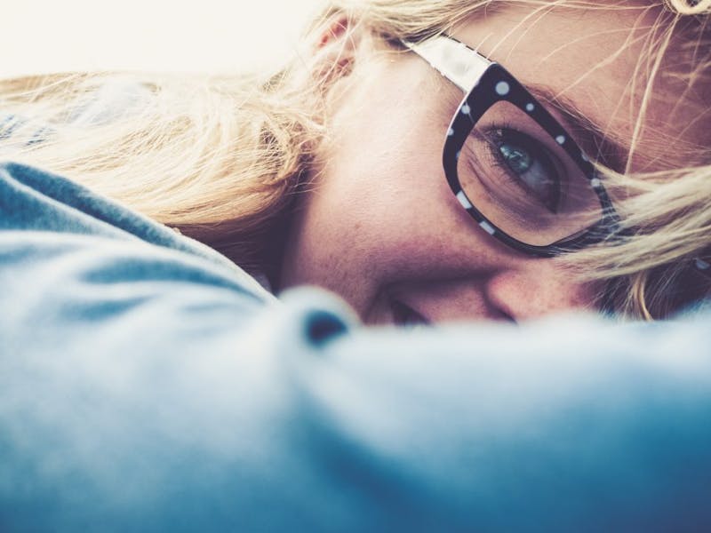 blond woman with glasses smiling and leaning on her shoulder