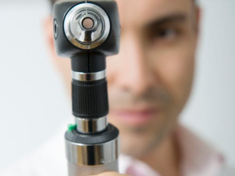 doctor holding a ophthalmoscope up to camera