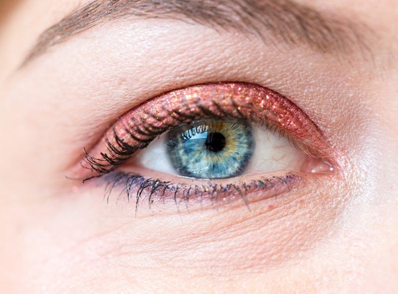 a close up of a woman's right eye with a pink glitter eyeliner