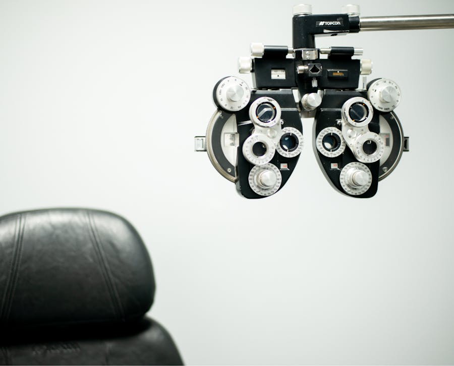 eye exam equipment alongside a chair in white room