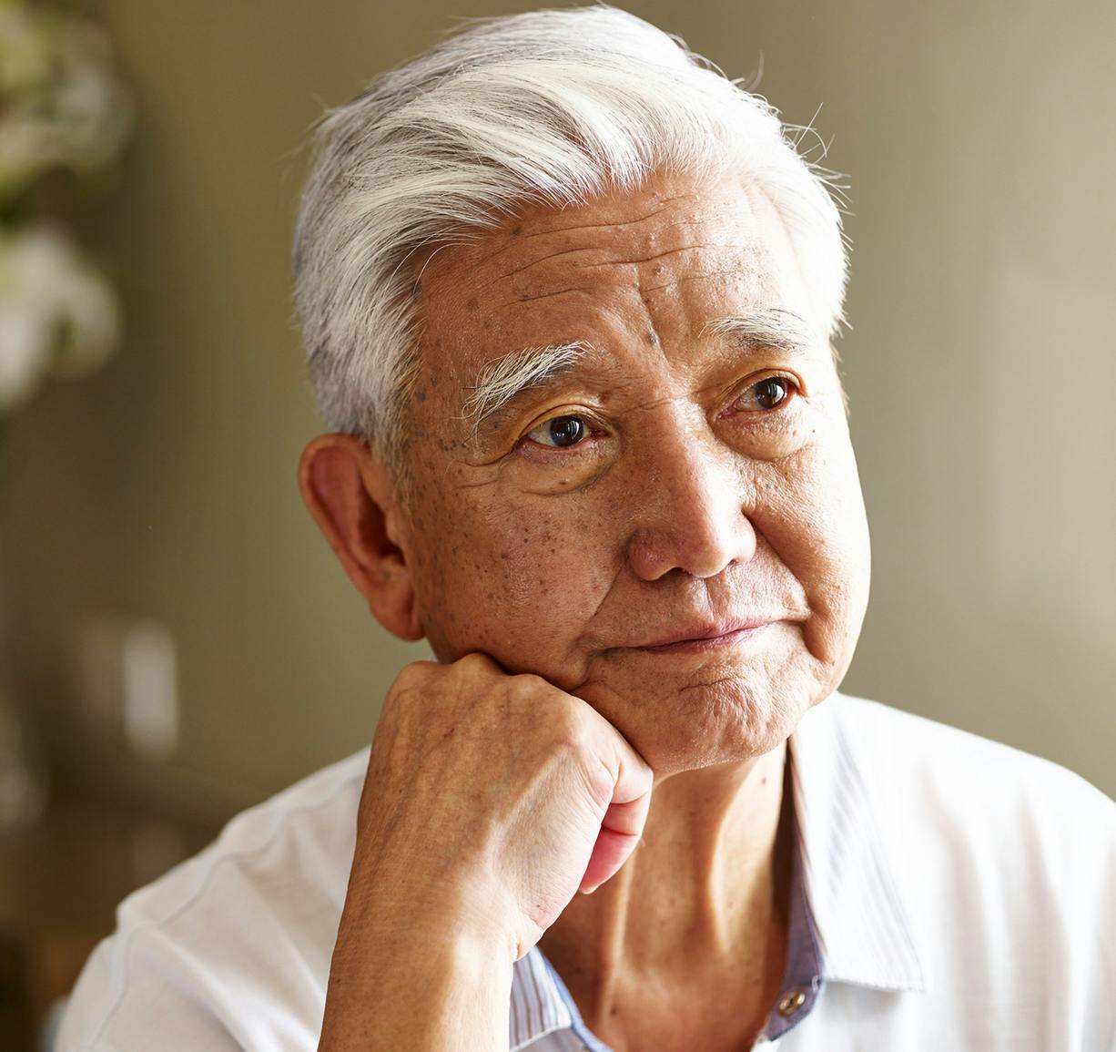 older man with white hair and a white shirt looking away