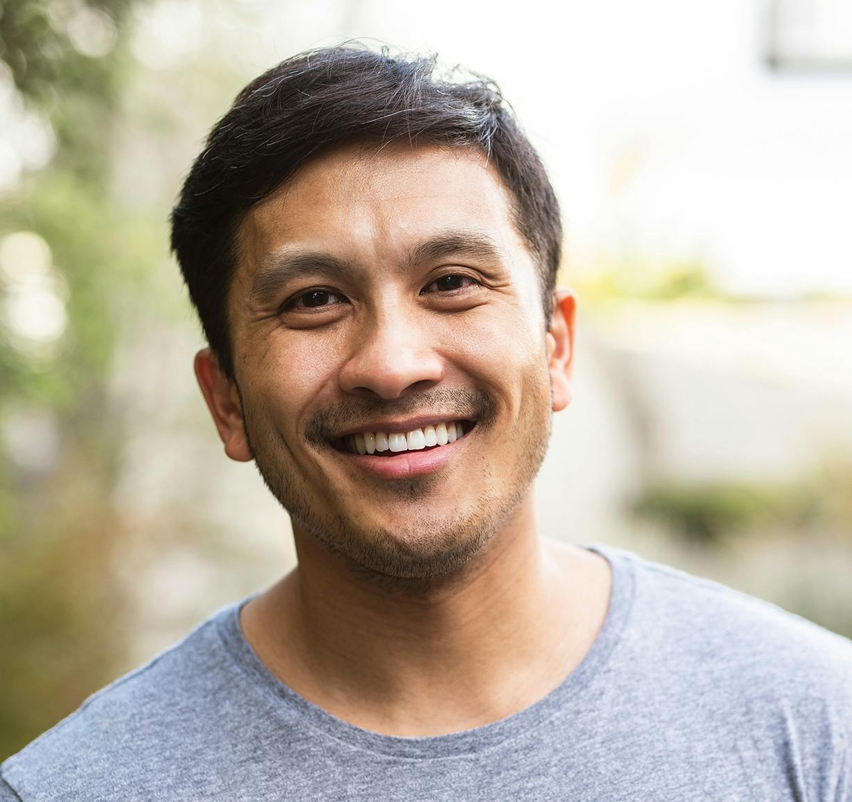 smiling man standing outside with a gray shirt