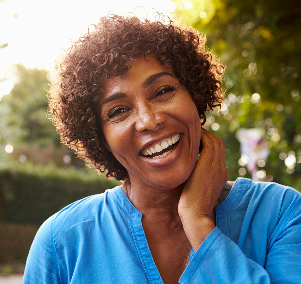 smiling woman with curly hair and blue shirt posing for a picture