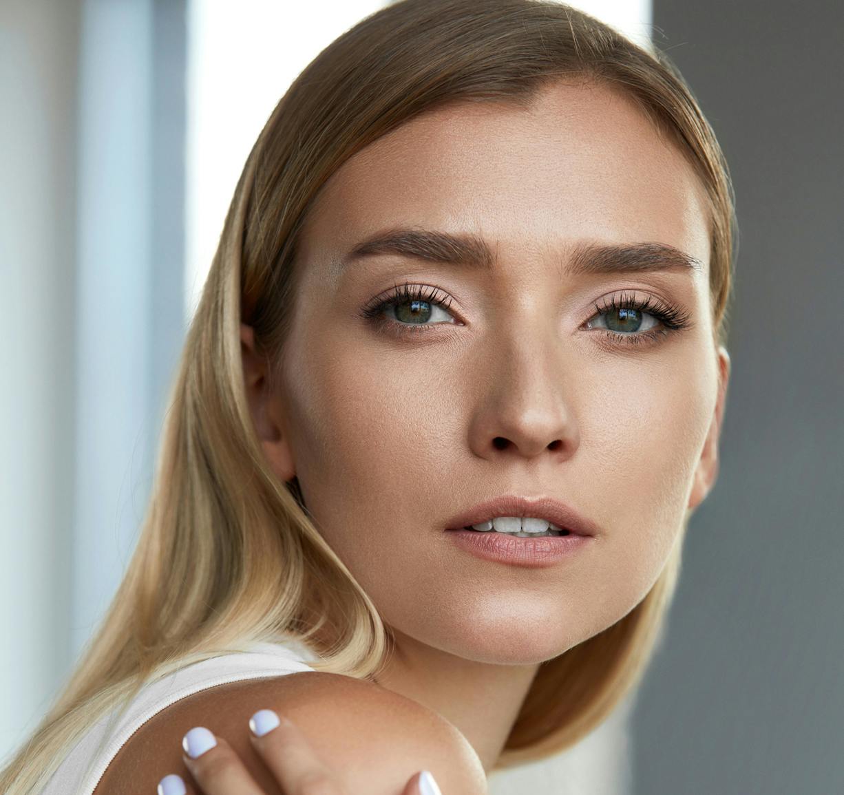 blond woman with white nails and a white top posing for a picture