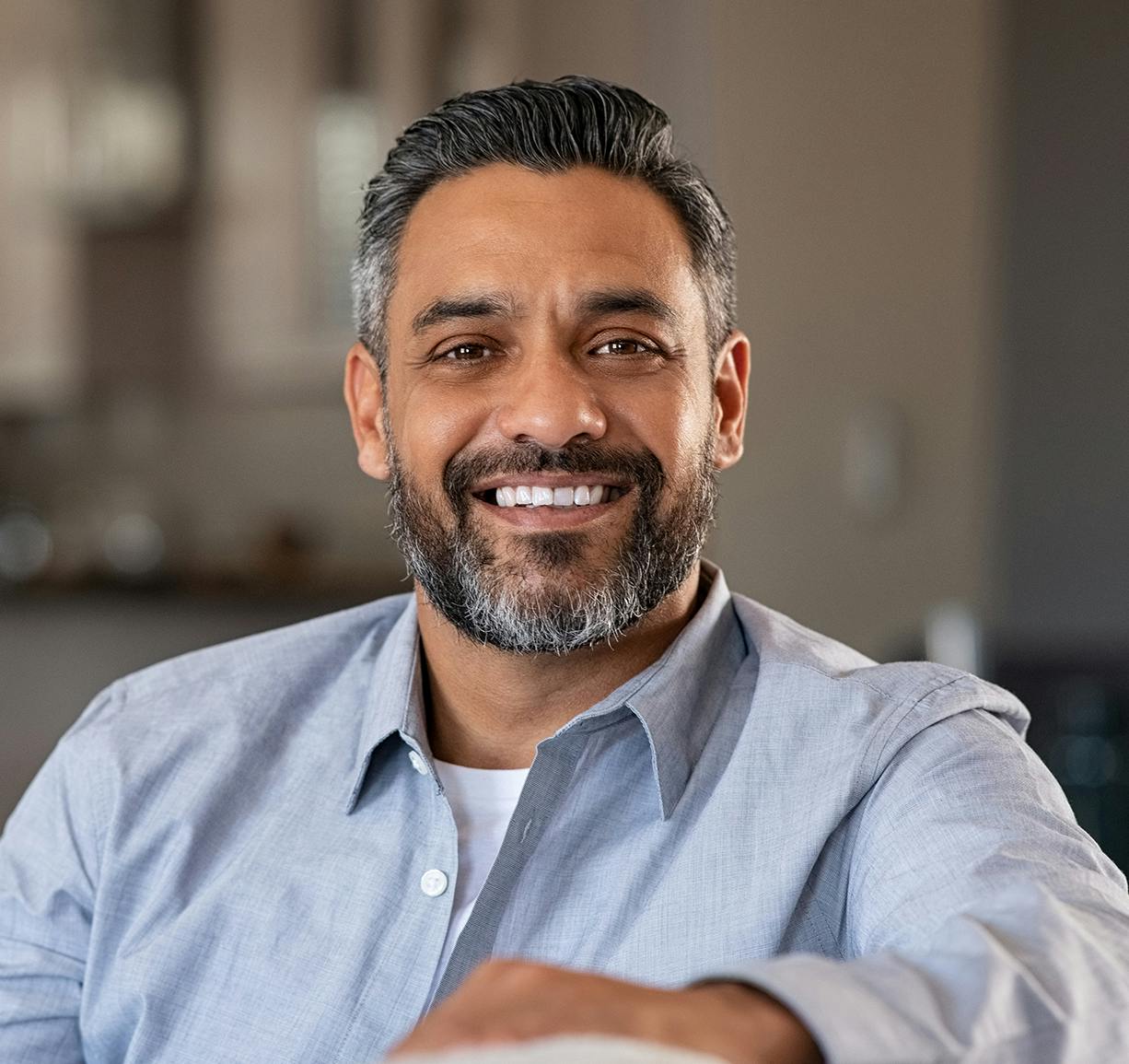smiling man with beard and gray hair sitting in a chair