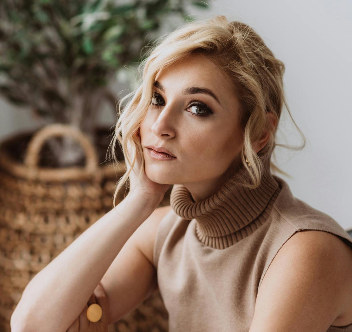 blond woman with a turtleneck sweater sitting on a couch