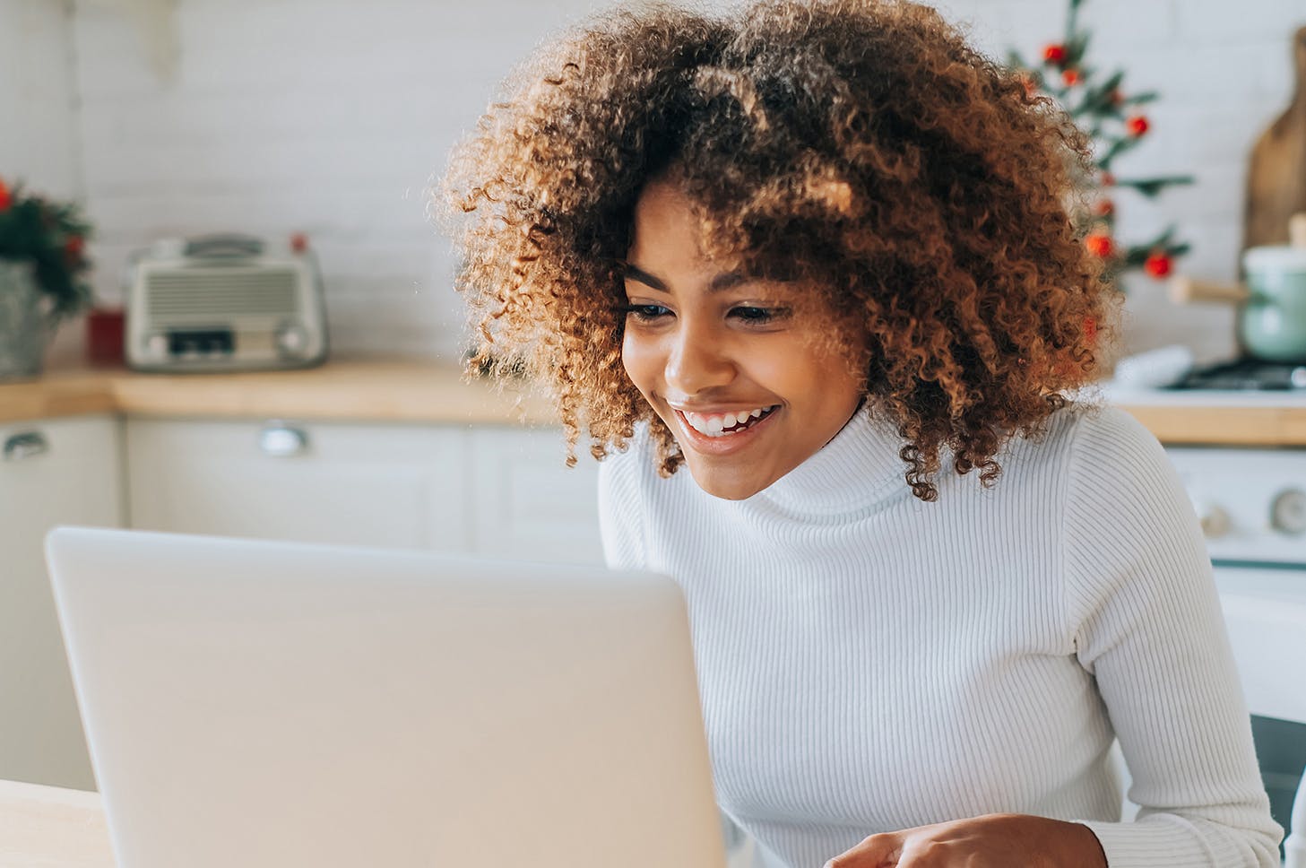 smiling woman using a laptop computer in a kitchen