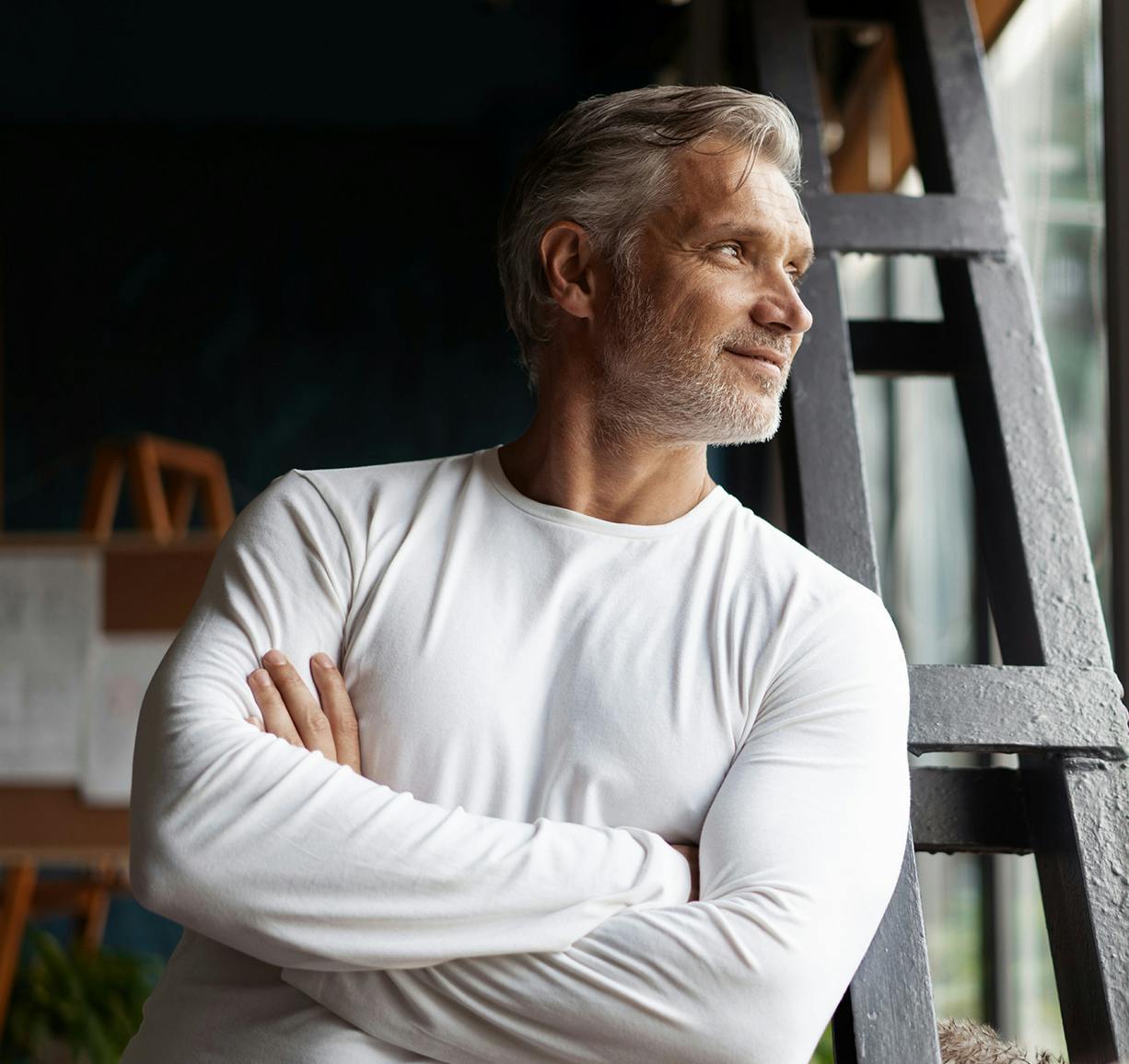 a man standing in front of a ladder with his arms crossed