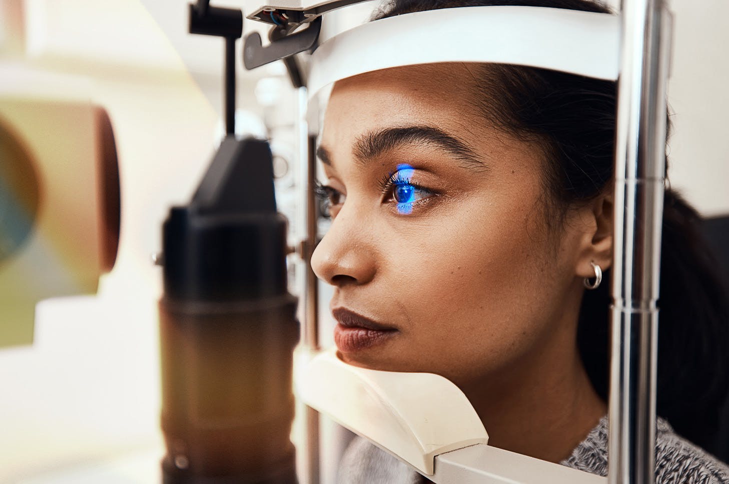 Lady resting her head on and looking into an eye exam scope