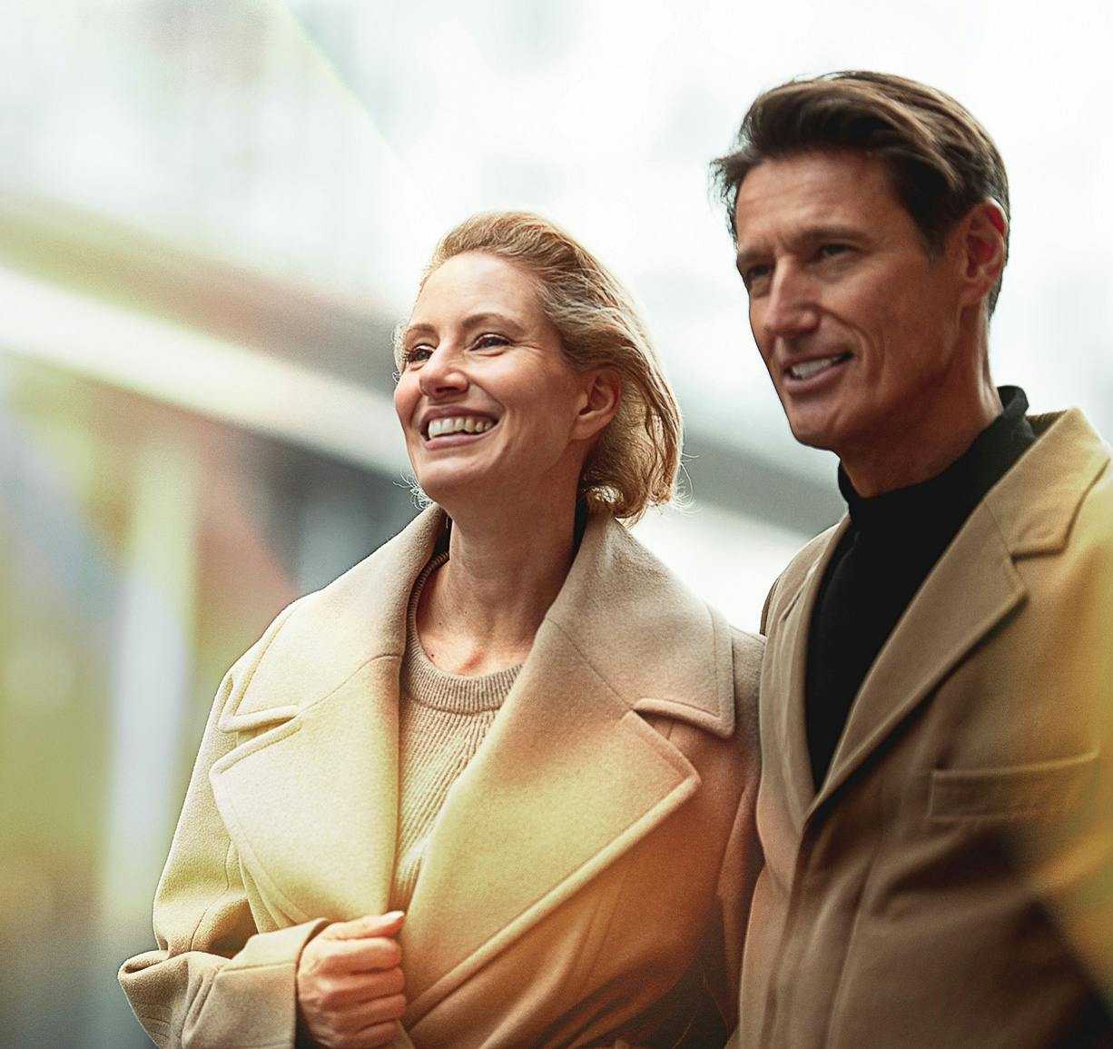 Man and woman together, looking out and smiling.