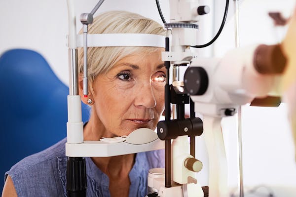 older lady resting her head on an eye exam scope