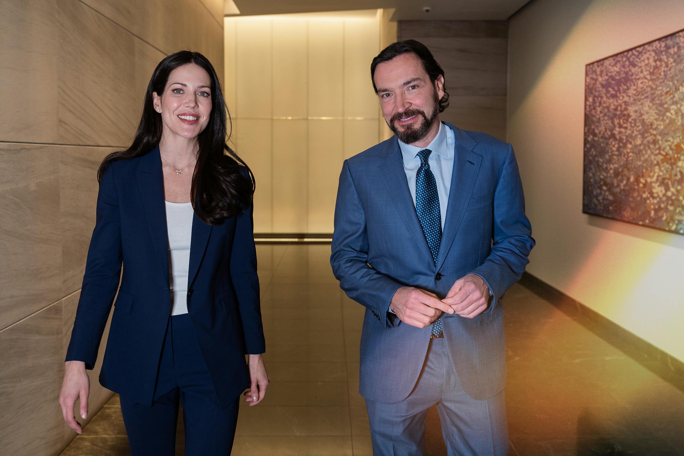 male and female doctor walking together while smiling and looking into the camera