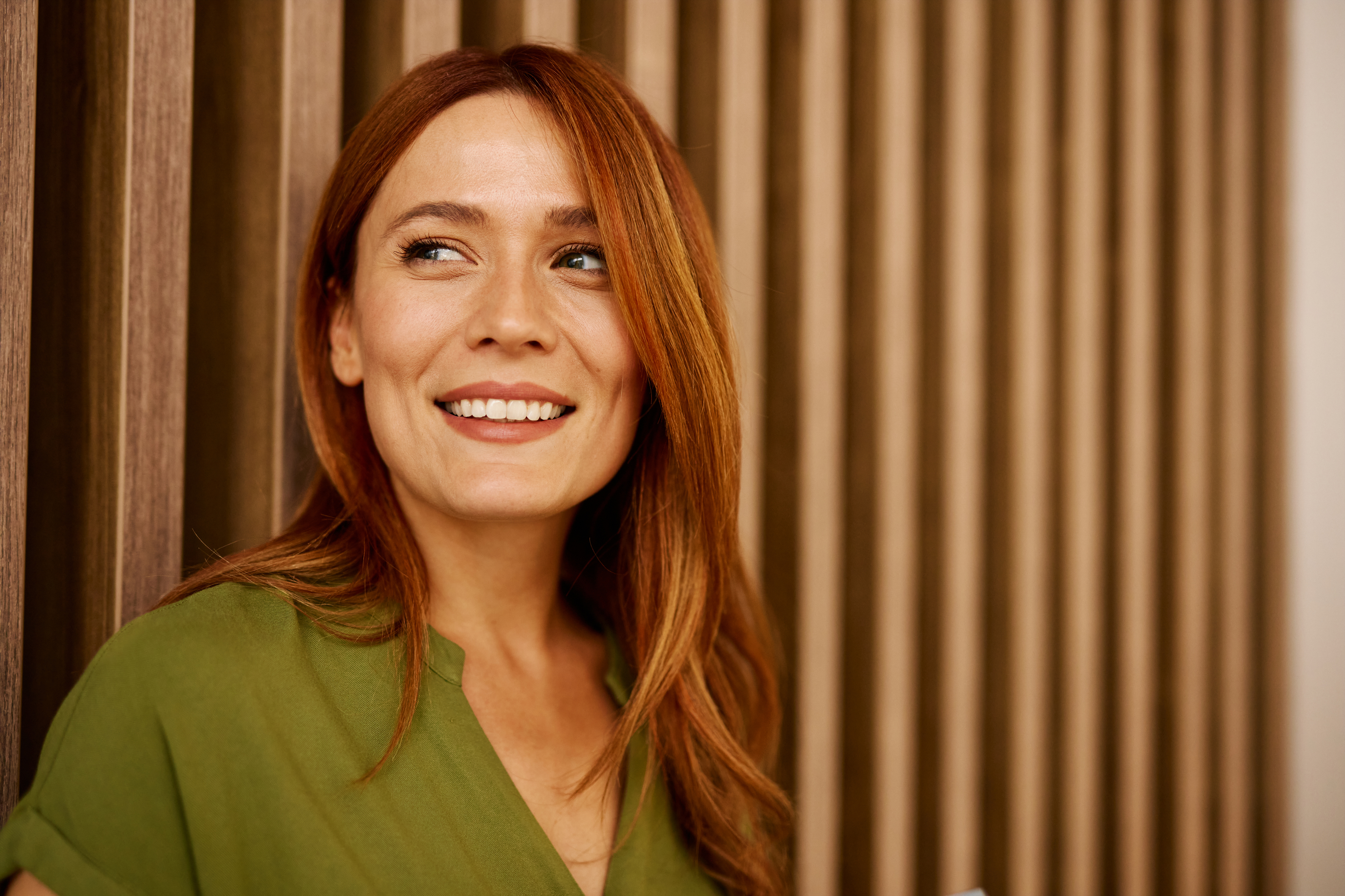 woman with red hair leaning on a wall
