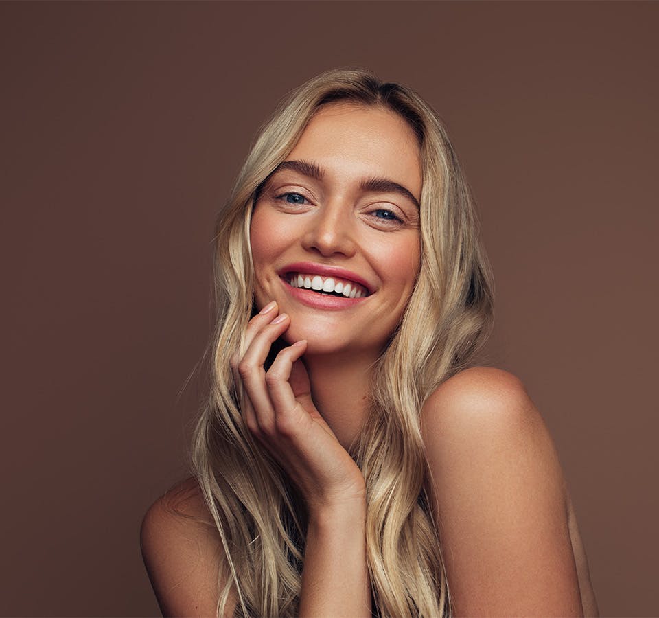 blonde woman touching her face and smiling