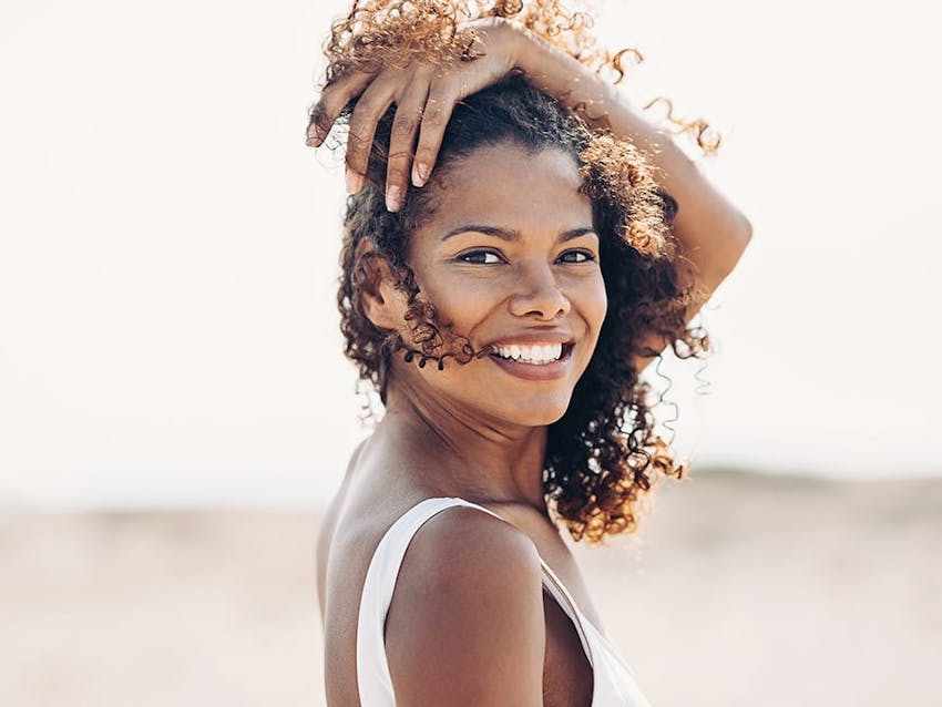 woman with dark hair on beach smiling