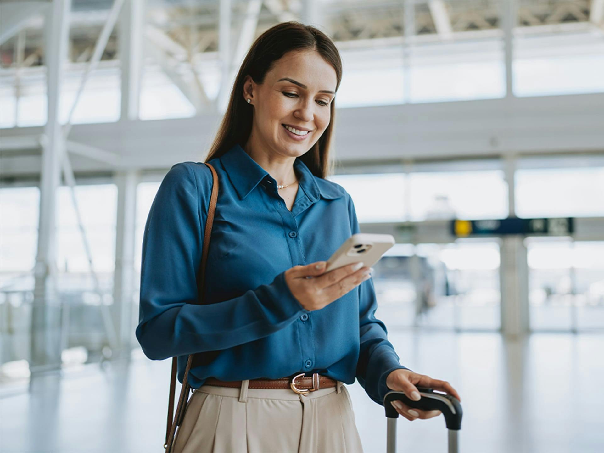 woman holding phone and rolling suitcase