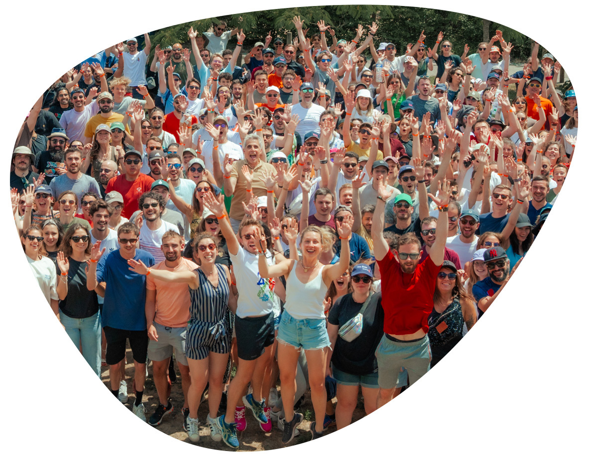 Foto grupal de cientos de personas celebrando al aire libre con brazos levantados