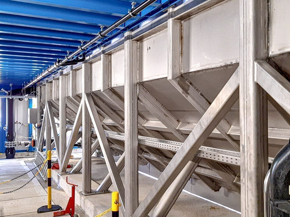 An industrial flotation plant with robust metal structures and blue ceiling elements, used for water treatment processes.