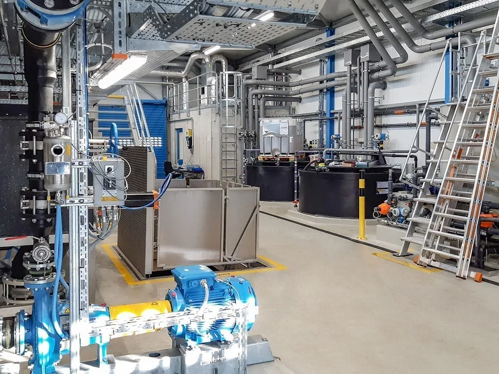 ARA Rhein Reference A spacious, modern industrial facility features a well-organized array of metal pipes, machinery, and equipment under bright fluorescent lighting, highlighting the clean, efficient workspace designed for manufacturing or processing operations.