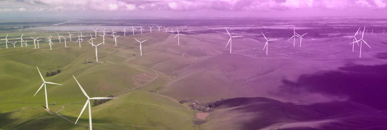 A vast field of green rolling hills is dotted with numerous white wind turbines under a sky with scattered clouds, showcasing sustainable energy and renewable power resources.