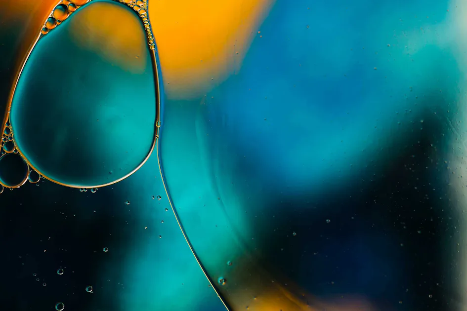 Biological Polutants Water A close-up of colorful oil bubbles floating on water, featuring vibrant hues of orange and blue against a soft, blurred background.