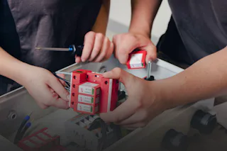 Service und Wartung Zwei Personen installieren gemeinsam rote Sicherungsrelais in einem Schaltschrank, während sie Werkzeuge verwenden, um die elektrischen Komponenten sorgfältig zu befestigen.