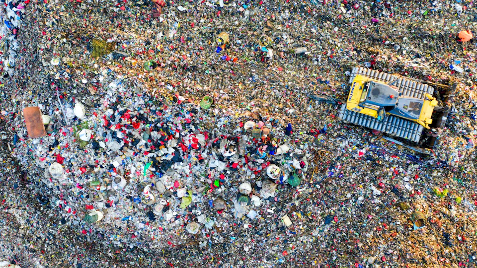 Landfill Leachate Aerial view of a landfill, filled with a vast array of colorful plastic waste and debris, being compacted by a large yellow bulldozer, emphasizing waste management and environmental pollution.
