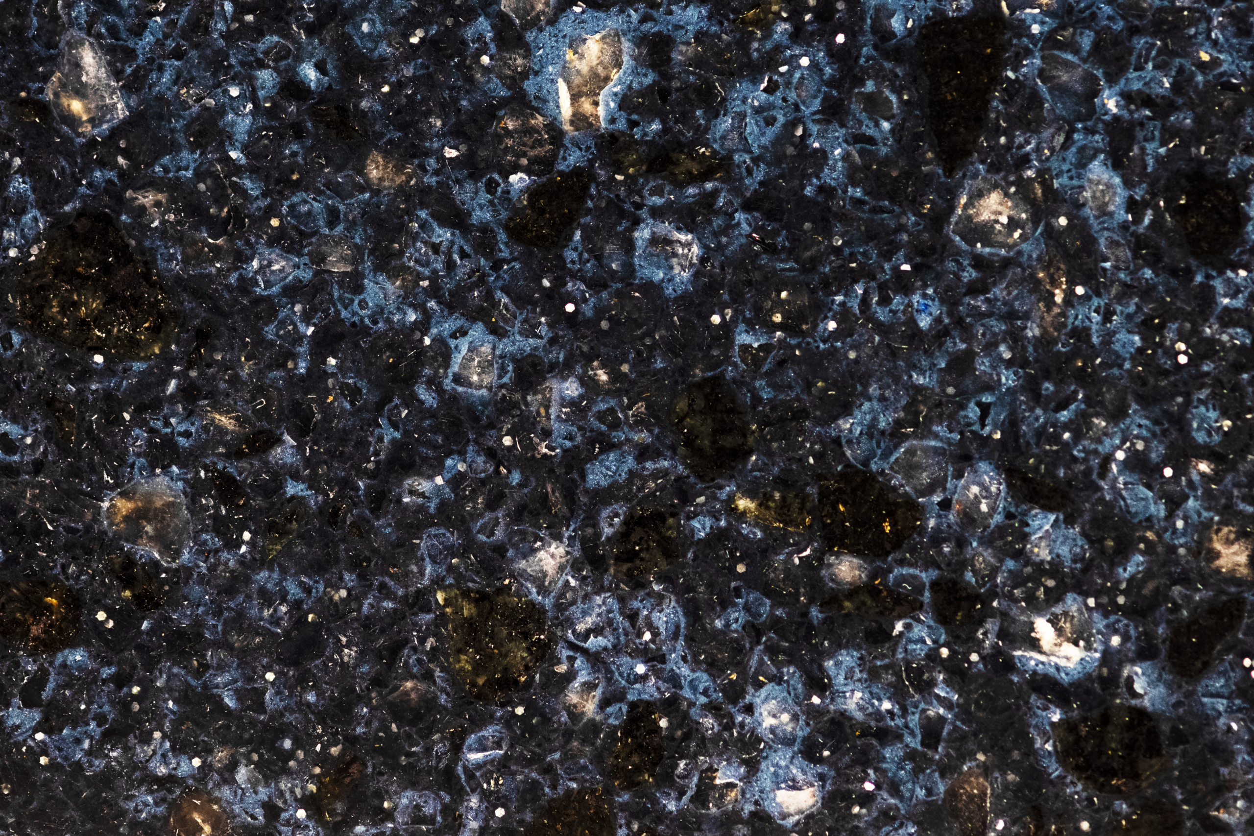 A close-up image of polished blue granite featuring a rich speckled pattern of dark blue, black, and white flecks, highlighting its intricate and natural stone texture.
