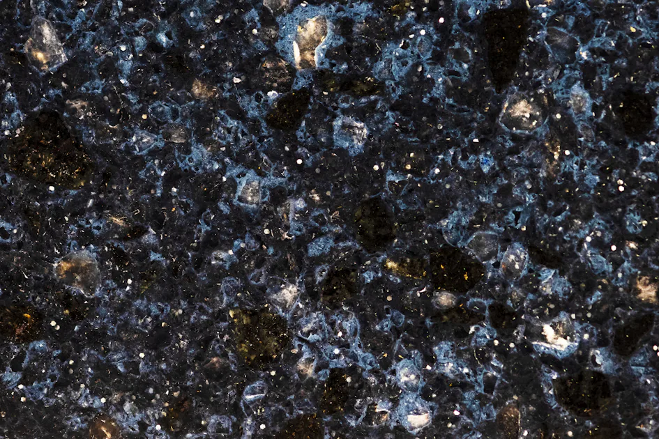 dunklen-gemarmorten-steins-scaled A close-up image of polished blue granite featuring a rich speckled pattern of dark blue, black, and white flecks, highlighting its intricate and natural stone texture.
