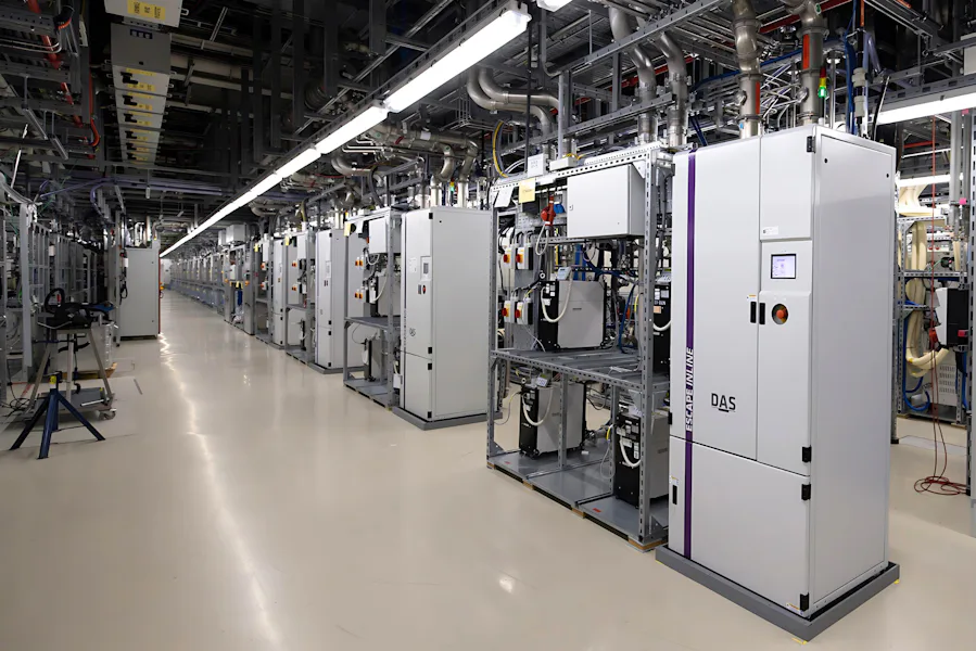 Subfab The image shows a spacious and well-lit data center with rows of advanced server racks and complex wiring systems running across the ceiling, illustrating high-tech infrastructure and efficient data management.