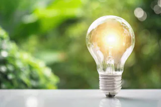 Case Studies_Innovations A glowing light bulb stands out against a blurred green background, conveying a sense of innovation and environmentally friendly energy.