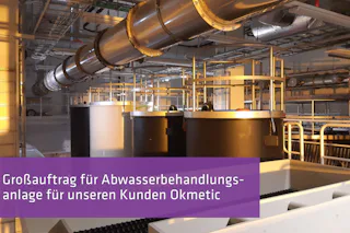 Großauftrag: Okmetic Eine industrielle Abwasserbehandlungsanlage mit mehreren großen Tanks und Rohrleitungen, umgeben von einem komplexen Netz aus Metallstrukturen, alles in einem gut beleuchteten, modernen Fabrikgebäude.