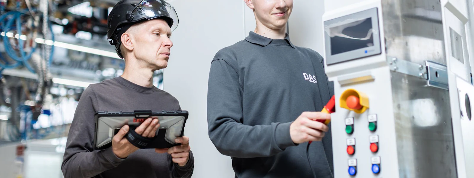 DAS service engineers at the switch cabinet Two workers in safety helmets operating a modern industrial control console