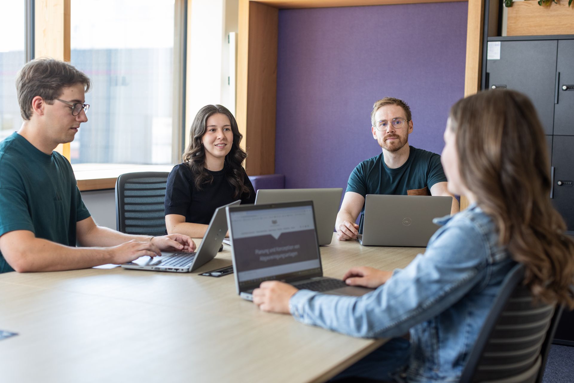 A group of young employees engaged in project planning and digital teamwork in a modern office landscape, highlighting agile working and innovation drivers within a vibrant startup culture.