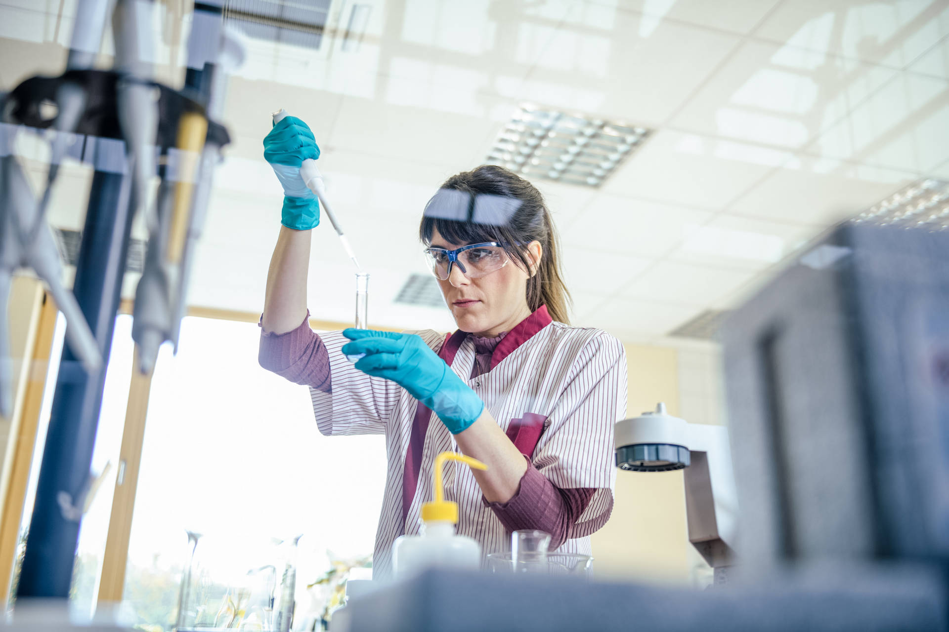 A scientist in a laboratory conducts a wastewater analysis while carefully using a pipette, wearing safety goggles and gloves.